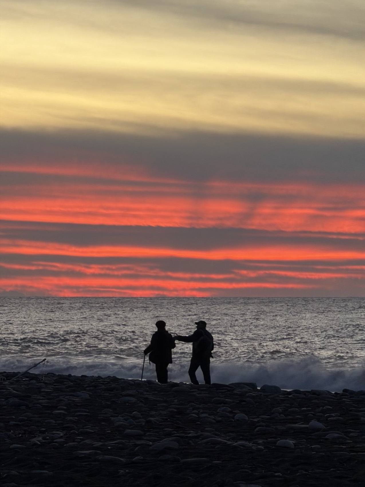 sunset on the batumi pebble beach, two people by the water